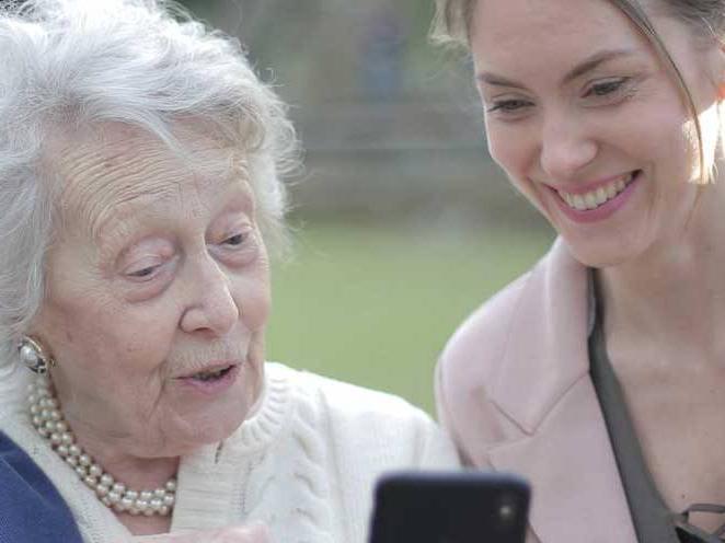 Woman is helping elder woman with phone technology