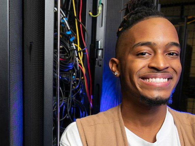 Man is smiling for picture with eletrical panel with wires hanging out behind him