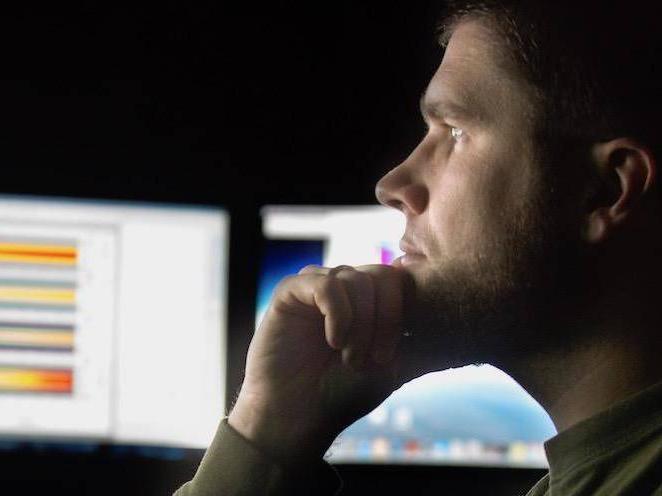 Man is looking at graphs on his computer monitors